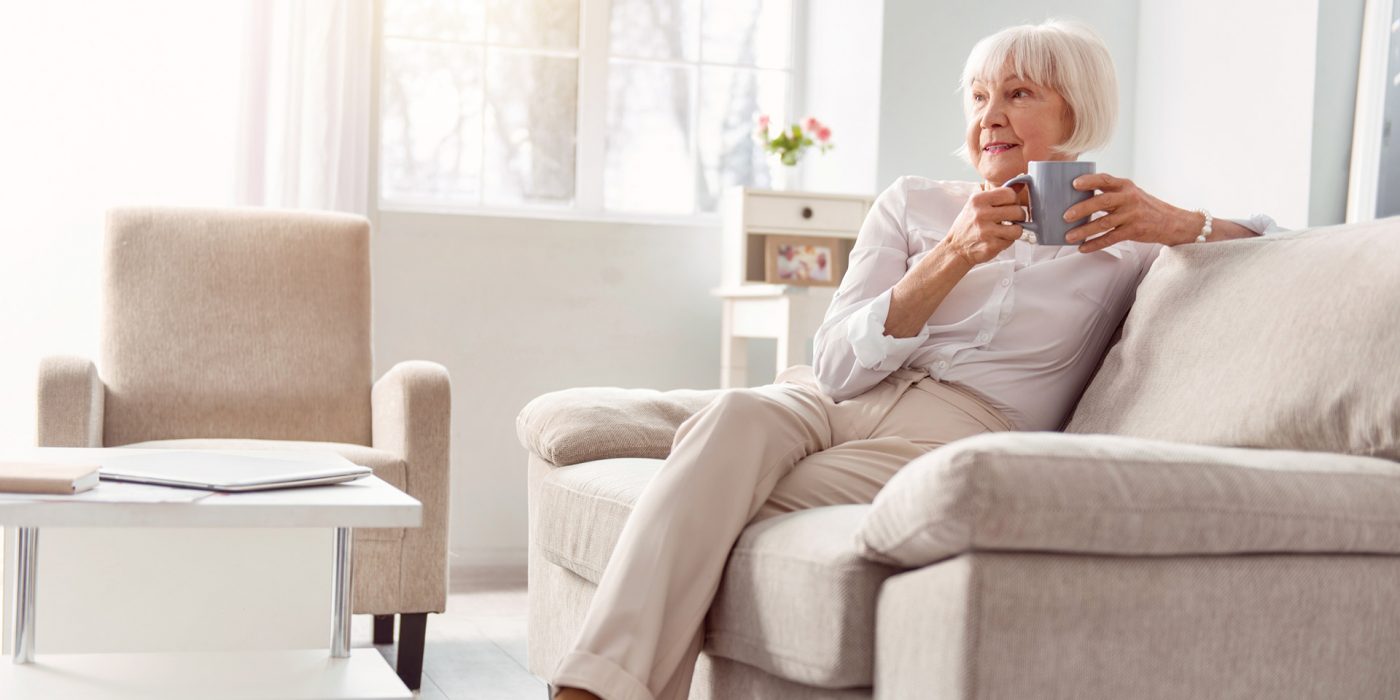 Petite elderly woman drinking coffee in her living room