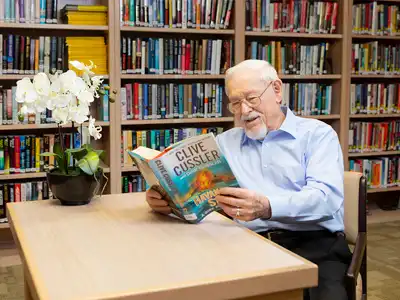 A gentleman reading a book in the library.